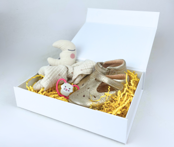 White gift box with baby shoes, plush toy and yellow shredded paper