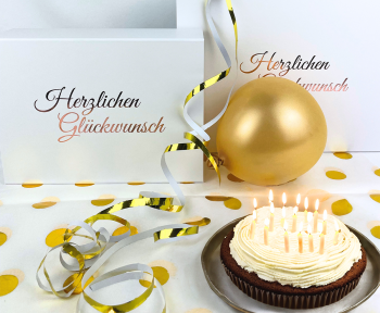 White birthday boxes with candle cake and golden decorations