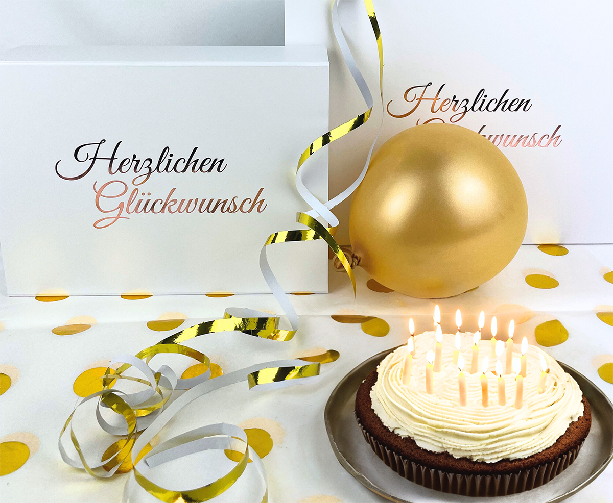 White birthday boxes with candle cake and golden decorations